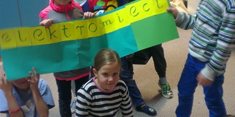 Powiększ grafikę: Dzieci trzymają niebiesko-zielony plakat z napisem ELEKTROŚMIECI.