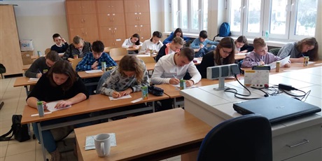 Powiększ grafikę: Uczniowie piszą w sali lekcyjnej test konkursowy.