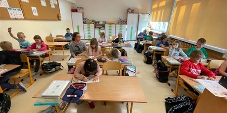 Powiększ grafikę: Uczniowie w sali lekcyjnej rozwiązują zadania przy swoich ławkach.