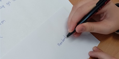 Powiększ grafikę: Widać rękę ucznia, który adresuje kopertę do władz Białorusi. 