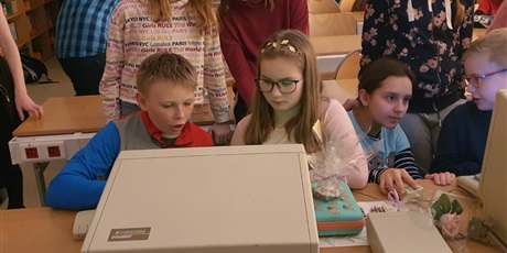 Powiększ grafikę: Uczeń i uczennica piszą wiadomość na starym komputerze. Są wpatrzeni w ekran.