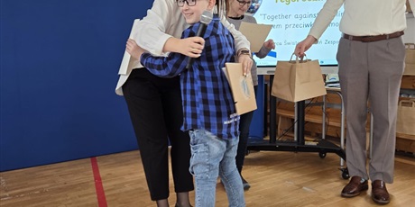 Powiększ grafikę: Na trzecim zdjęciu uwieczniony jest moment wręczania nagrody. Uczeń odbierając dyplom przytula się do nauczycielki. 