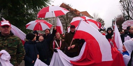 Powiększ grafikę: SP nr 82 w Gdańsku podczas Parady Niepodległości z biało-czerwonymi flagami i parasolami. 