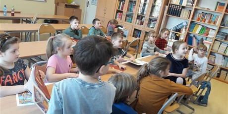 Powiększ grafikę: Uczniowie klasy pierwszej obserwują starszych uczniów i bibliotekarza.