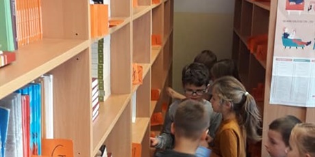 Powiększ grafikę: Uczniowie klasy pierwszej oglądają książki w bibliotece.