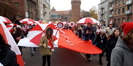 Powiększ grafikę: Społeczność SP82 podczas parady niepodległości - wszyscy trzymają biało-czerwone parasolki.