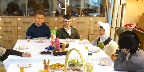 Powiększ grafikę: Uczniowie klasy 6a przebrani za bohaterów książki "Hobbit" siedzący przy stole z jedzeniem.