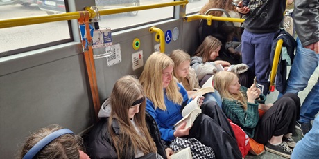 Powiększ grafikę: Uczniowie w autobusie czytają książki.