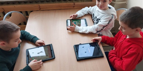 Powiększ grafikę: Troje uczniów korzysta z tabletów. 