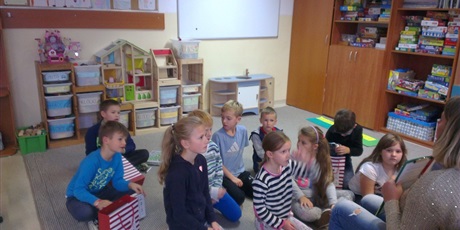 Powiększ grafikę: Dzieci siedzą na dywanie w świetlicy i rozmawiają z nauczycielem.