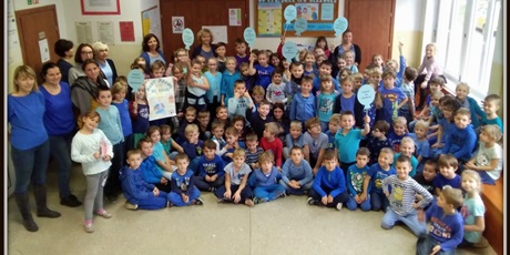 Powiększ grafikę: Uczniowie i nauczyciele pozują ubrani na niebiesko.
